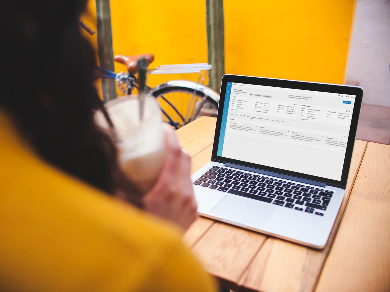 over-shoulder-mockup-of-a-woman-using-a-macbook-on-a-wooden-table.png
