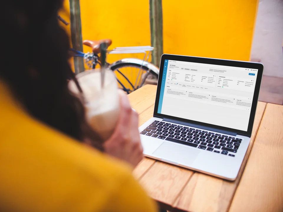 over-shoulder-mockup-of-a-woman-using-a-macbook-on-a-wooden-table.png